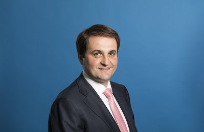 Chef der Staatskanzlei Nathanael Liminski freundlich lächelnd - Hintergrund blau.