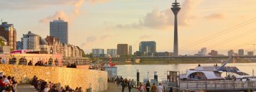 Menschen sitzen am Rheinufer bei Sonnenuntergang