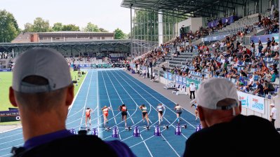 Blick von der Tribüne auf Sportler auf der Rennbahn