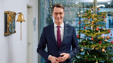 Ministerpräsident Hendrik Wüst steht auf einem Flur in einem Krankenhaus vor einem Weihnachtsbaum 