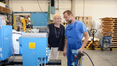Ministerpräsidentin Kraft steht mit einem Mitarbeiter vor einer großen Maschine