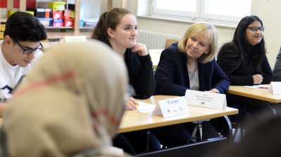 Ministerpräsidentin Hannelore Kraft sitzt zwischen Schülerinnen und Schülern im Klassenraum