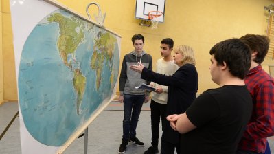 Ministerpräsidentin Hannelore Kraft mit Schülern zeigend vor einer Weltkarte