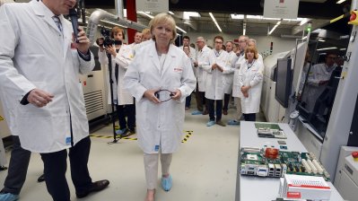 Ministerpräsidentin Kraft sthet bei ihrem Rundgang mit einem Mitarbeiter vor einem Tisch, auf dem ein PC-Mainboard offen liegt