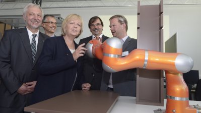 Ministerpräsidentin Kraft betrachtet einen orangenen Roboterarm