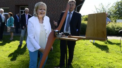 Ministerpräsidentin Hannelore Kraft steht vor einem Holzflugzeug
