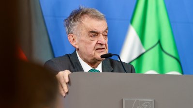 Minister Reul spricht an einem Rednerpult vor Flaggen