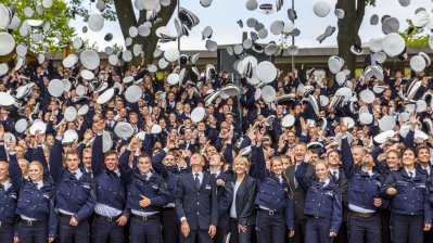 Polizistenanwärter werfen ihre Mütze in die Luft, mittig stehen Ministerpräsidentin Hannelore Kraft und dahinter Innenminister Ralf Jäger