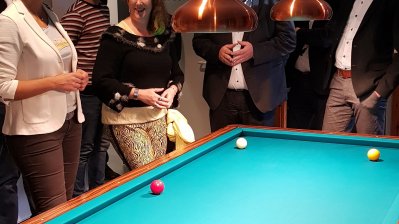 Staatssekretärin Andrea Milz steht mit einer Gruppe um einen Billiardtisch herum.
