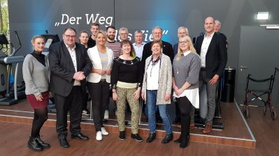 Gruppenfoto mit Staatssekretärin Andrea MIlz, auf der Rückwand steht weiß auf grau: "Der Weg ist das Ziel!"