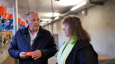 Staatssekretärin Andrea Milz im schwarzen Mantel und hellgelben Schal im Gespräch mit einem Mann im blauen Overall und weißen Hemd.