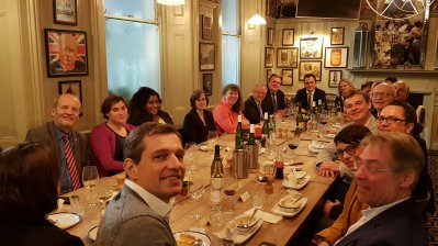 Staatssekretärin Milz sitzt mit dem Sportausschuss in London beim Essen an einem großen Tisch zusammen. An Wänden hängen überall eingerahmte Bilder.