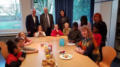 Staatssektretärin Milz sitzt mit Mitgliedern des Aachener Förderverein Integration durch Sport e.V. an einem Tisch. Auf der linken Seite des Tisches sitzen Kinder.