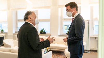 Zwei Männer sind im Gespräch in einem hellen Raum mit weißer Sitzgarnitur