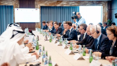 Eine große Tafel mit Teilnehmern, die sich gegenüber sitzen