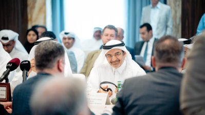 Eine große Tafel mit Teilnehmern, die sich gegenüber sitzen