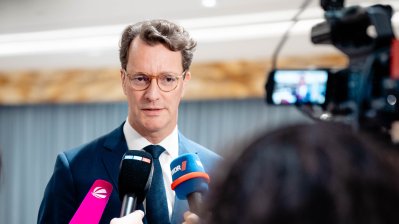 Ministerpräsident Wüst gibt ein Pressestatement, im Vordergrund Mikrofone deutscher Medien