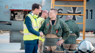 Ministerpräsident Wüst und ein Soldat unterhalten sich vor einem Kampfjet