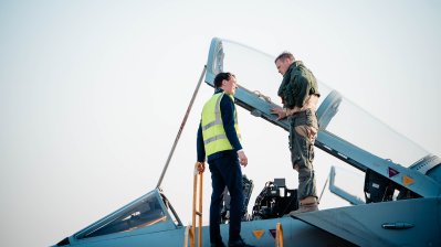 Ministerpräsident Wüst und ein Soldat stehen auf einem Kampfjet an der Einstiegsluke