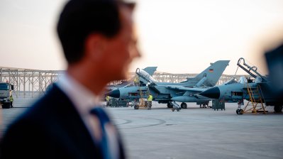 Ministerpräsident Wüst unscharf im Vordergrund, im Hintergrund mehrere Kampfjets