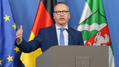 Eine Person spricht am Rednerpult auf einer Pressekonferenz