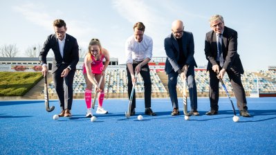 Eine Personengruppe posiert mit Hockeyschlägern