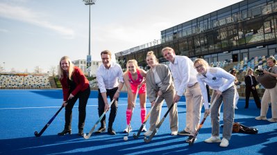 Eine Personengruppe posiert mit Hockeyschlägern