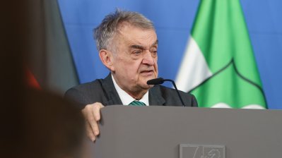 Minister Reul spricht an einem Rednerpult vor Flaggen