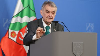 Minister Reul spricht an einem Rednerpult vor Flaggen