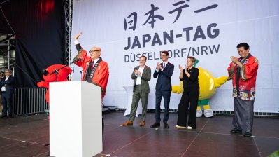 Ein Mann in traditionell japanischer Kleidung hält auf der Bühne einer Ansprache