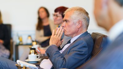 Besprechungssituation in einem festlichen Raum, der Doyen hört gespannt zu