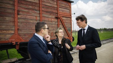 MP Wüst und die Antisemitismusbeauftragte Sylvia Löhrmann stehen mit dem Leiter der Führung vor einen Zugwagon