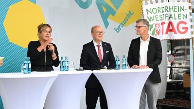 Landtagspräsident Kuper, die stellvertrende Ministerpräsidentin Neubaur und Oberbürgermeister Tilman Fuchs bei der Eröffnung auf einer Bühne