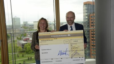 Gaby Schäfer vom Verein sunshine4kids e.V. und der Chef der Staatskanzlei, Franz-Josef Lersch-Mense halten gemeinsam den Check hoch