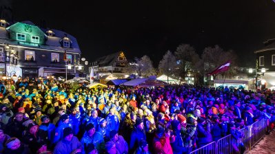 Das Publikum zur Eröffnungsfeier, je nach Bühnenbeleuchtung blau, pink, gelb oder weiß angeleuchtet.