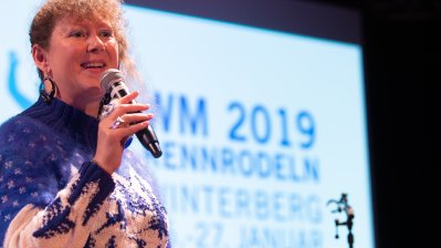 Staatssekretärin Andrea Milz mit Mikrofon in der rechten Hand auf der Bühne.