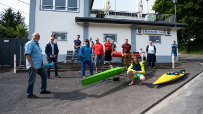Staatssekretärin Milz mit Vereinsmitgliedern und ein paar Kanus vor dem Vereinsgebäude.