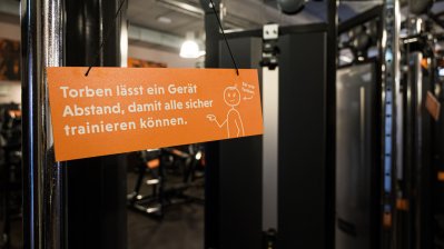 ein oranges Schild mit einem weißen Strichmännchen namens Torben und weißen Text dient alls Abstandshalter beim Training.
