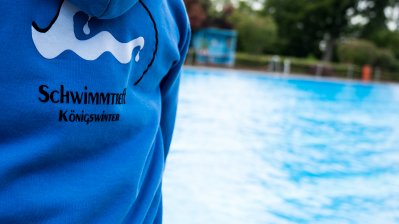 Ein Mitglied vom Schwimmbad Königswinter steht am Beckenrand eines offenen Schwimmbeckens.