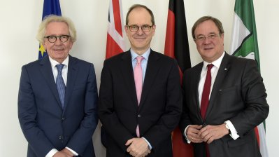 Von links nach rechts: EuropamInister Holthoff-Pförtner, der britische Botschafter Sir Sebastian Wood und Ministerpräsident Armin Laschet. Im Hintergrund die Flaggen von Europa, des Vereinigten Königreiches, Deutschland und Nordrhein-Westfalen. 