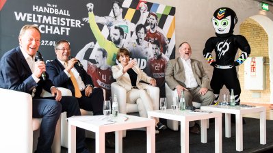 Ministerpräsident Laschet mit drei weiteren Personen in einer Gesprächsrunde zusammensitzend. Rechts im Hintergrund das schwarz-weiße Maskottchen.