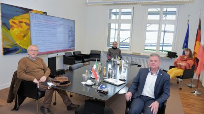 Staatsekretärin Milz in einem Besprechungsraum mit 3 Herren an einem schwarzen Besprechungstisch..