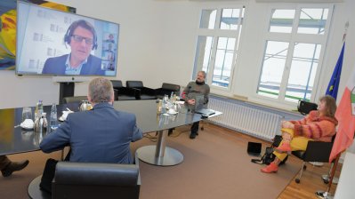 Staatssekretärin Milz nimmt mit 3 Herren in einem Besprechungsraum an einer Videokonferenz teil.