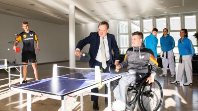 Armin Laschet spielt mit einem jungen Sportler im Rollstuhl Tischtennis.