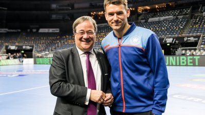 Ministerpräsident Armin Laschet mit einem Handballspieler auf der Spielfläche.