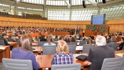 Zuhörer und Gäste sitzen im Plenarsaal auf den Plätzen der Abgeordneten