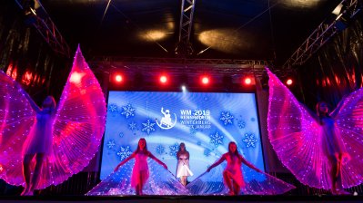 Showauftritt von 5 jungen Damen mit transparent-pinkfarbenen Flügeln, die überall mit kleinen, blau-leuchtenden LEDs verziert sind.
