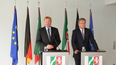 Innenminister Ralf Jäger und Regierungssprecher Thomas Breustedt stehen nebeneinander jeweils hinter einem Stehpult