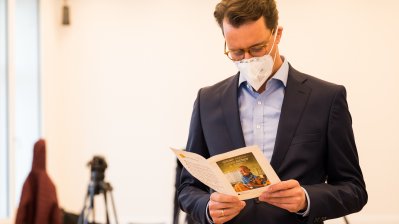 Ministerpräsident Hendrik Wüst schaut in das Gesangsheft