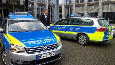 Bild mit 2 Polzeifahrzeugen und neongelben Streifen vor dem Innenministerium NRW
